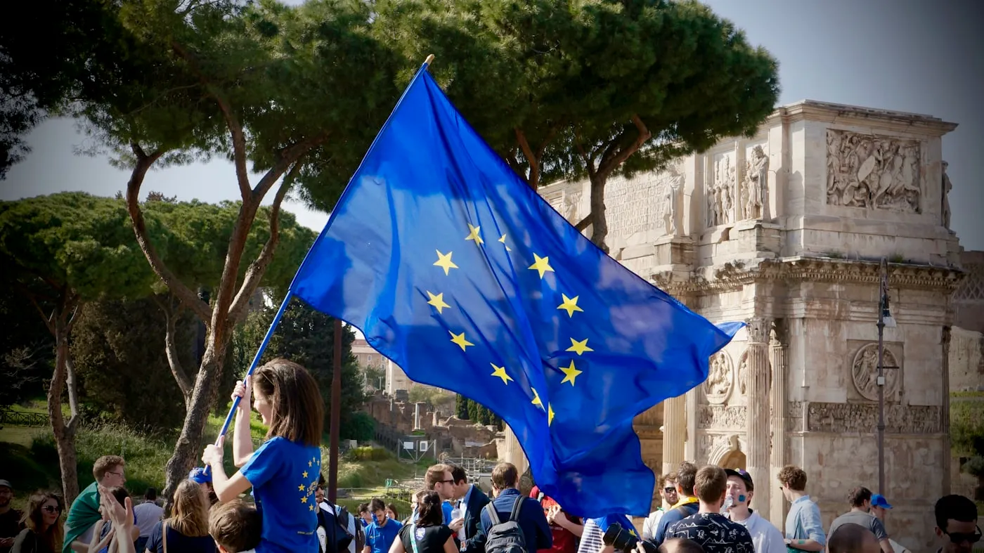 A student holding a European flag in front of a crowd